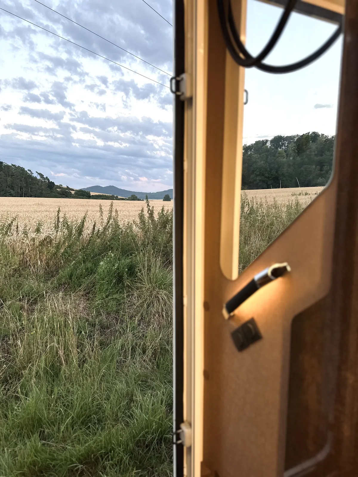 Geöffnete Aufbautür mit Blick über ein Kornfeld